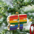 Pride SF glass ornament hanging on a Christmas tree, hand-painted rainbow colors.